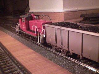 A short but still very detailed red locomotive coupled to the same coal truck.